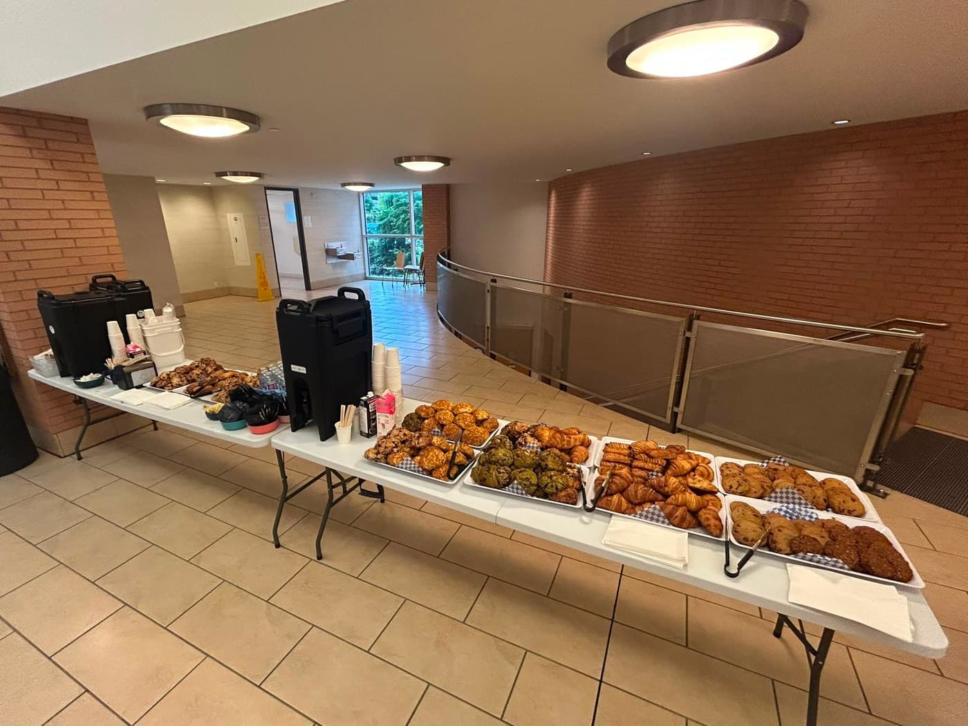 catering setup on campus — coffee urns with croissants, muffins and cookies laid out